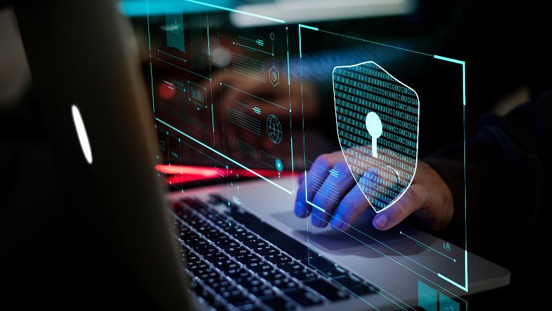 Hand am Laptop mit digitalem Sicherheitsschirm