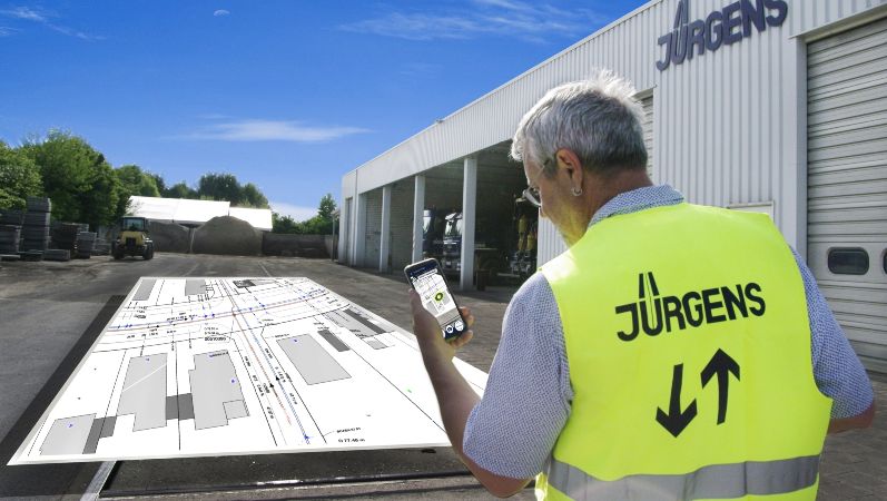 Ein Mitarbeiter der Hermann Jürgens Straßen- und Tiefbauunternehmen GmbH & Co. KG demonstriert die entwickelte App, mit deren Hilfe per Augmented Reality pdf-Baupläne direkt vor Ort an die entsprechende Stelle projiziert werden können.